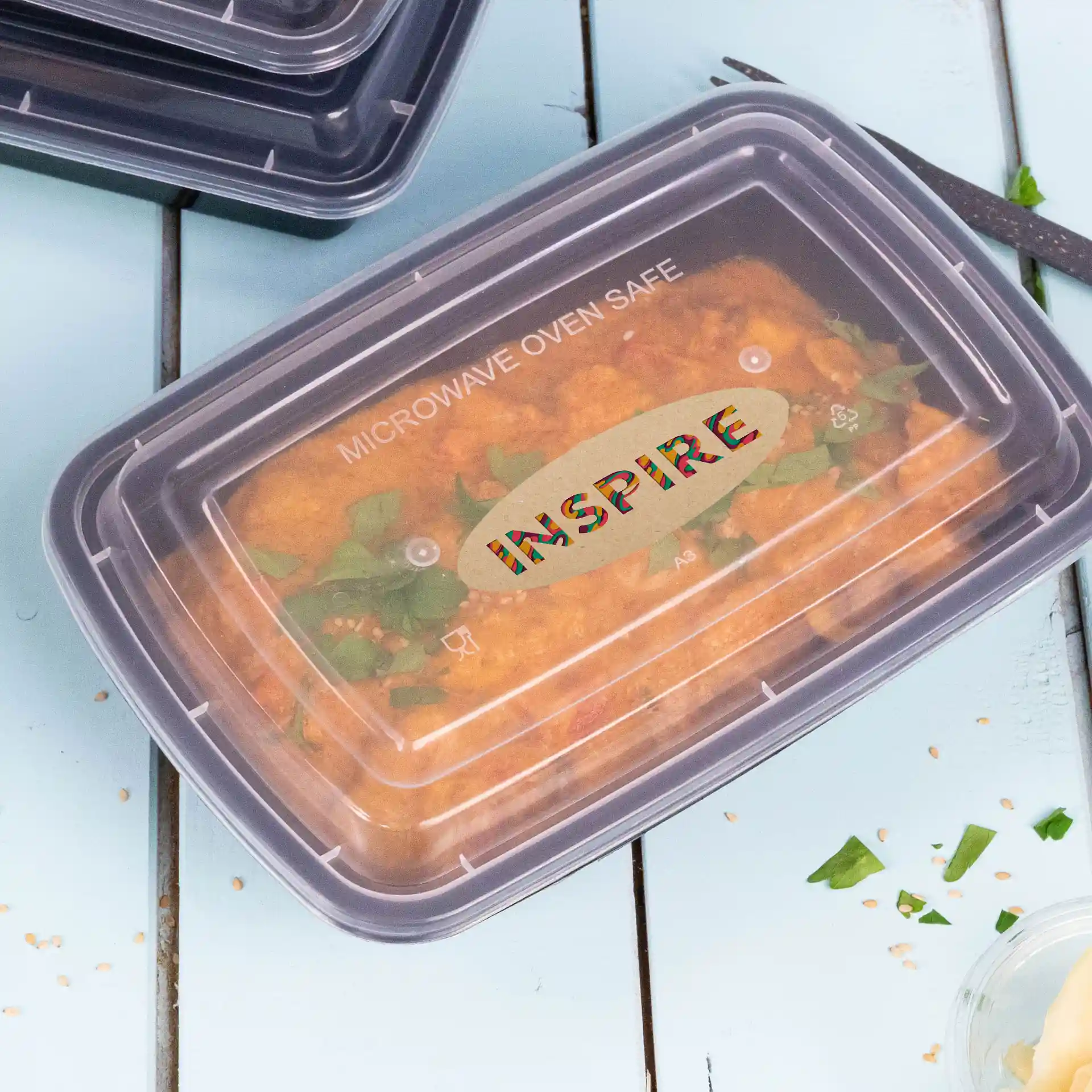 Behälter mit klarem Deckel, der Lebensmittel zeigt, beschriftet mit "Mikrowellengeeignet" und "Inspire" oben.