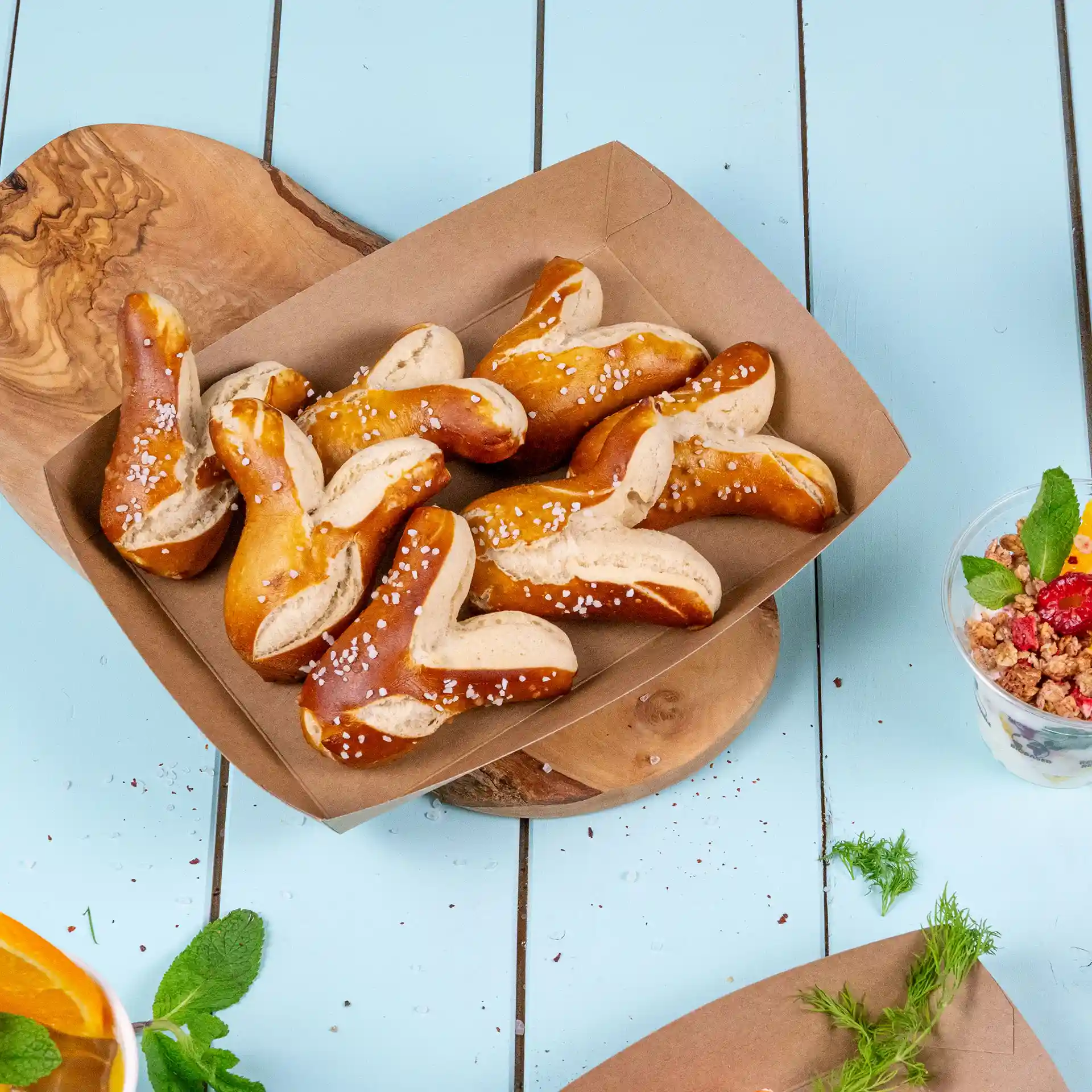 Un vassoio di cartone marrone riempito con diversi pezzi di pretzel guarniti con sale grosso.