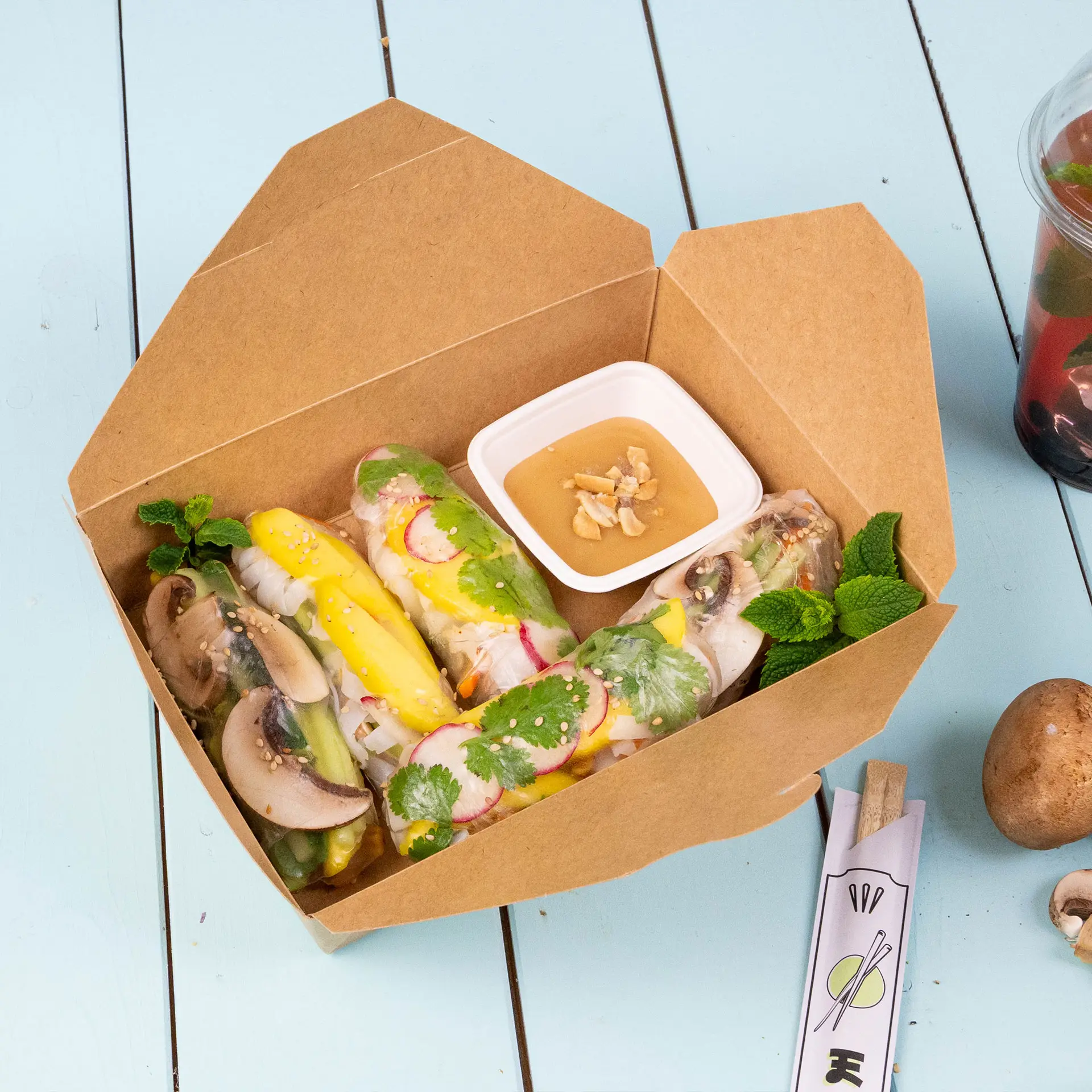 Boîtes en carton marron à emporter avec un couvercle pliable ; comprend des baguettes, une salade et une sauce dans un cadre en bois.