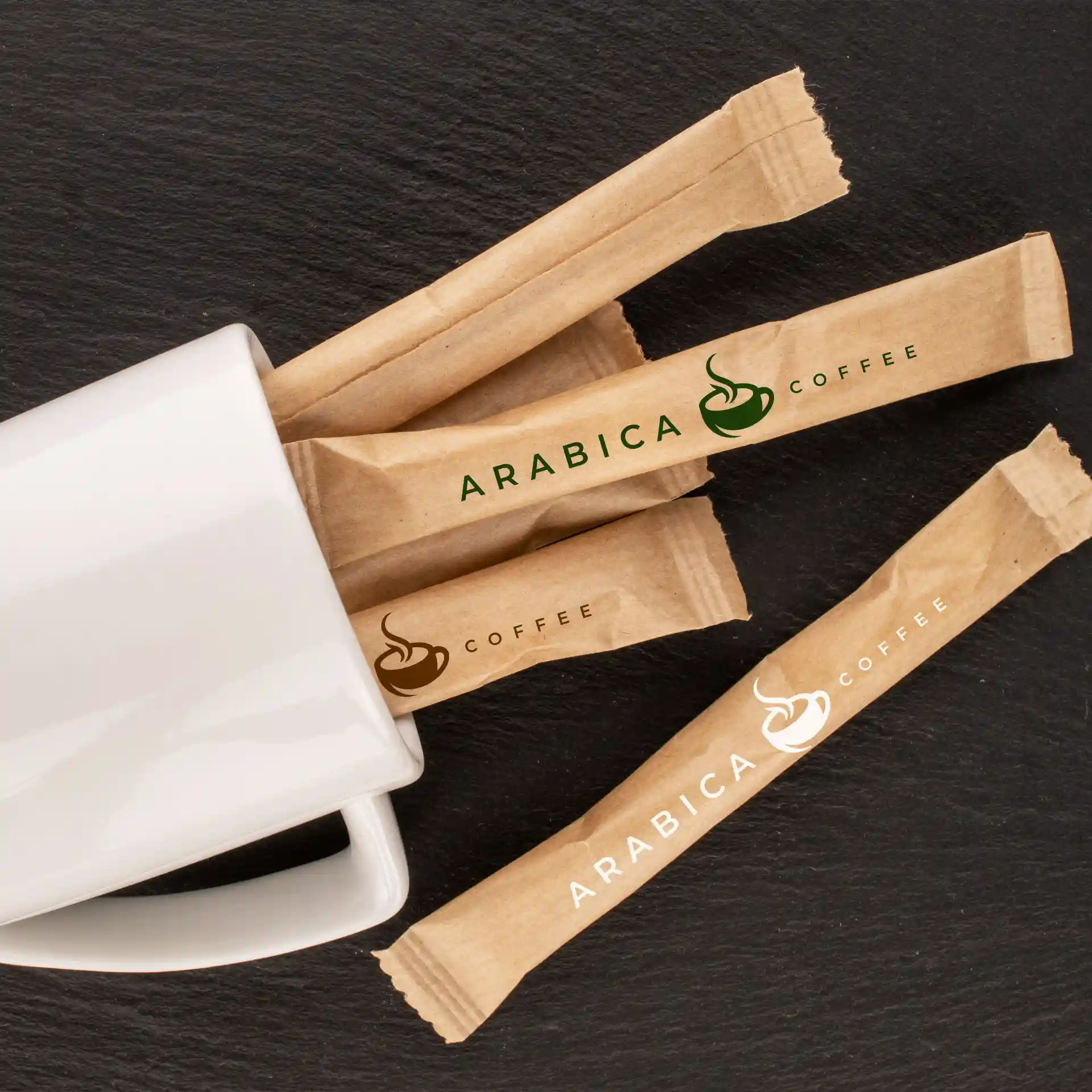 Ein weißer Becher mit mehreren Zuckersticks mit dem Logo, auf einer dunklen Oberfläche platziert.