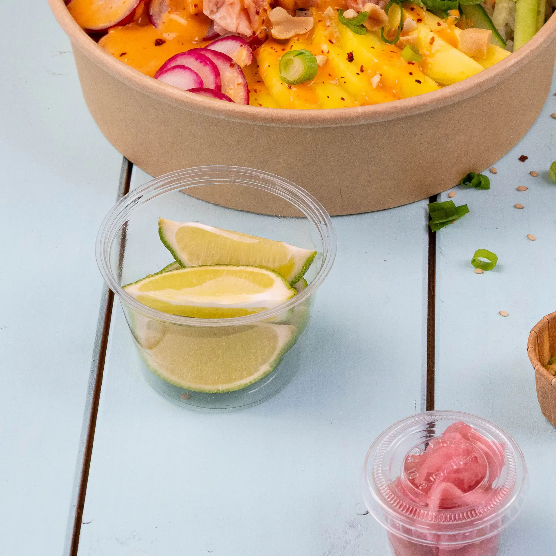 Gobelets portion en PLA bio contenant des tranches de citron vert pour la vinaigrette ou le dip, placés à côté d'un bol de salade.