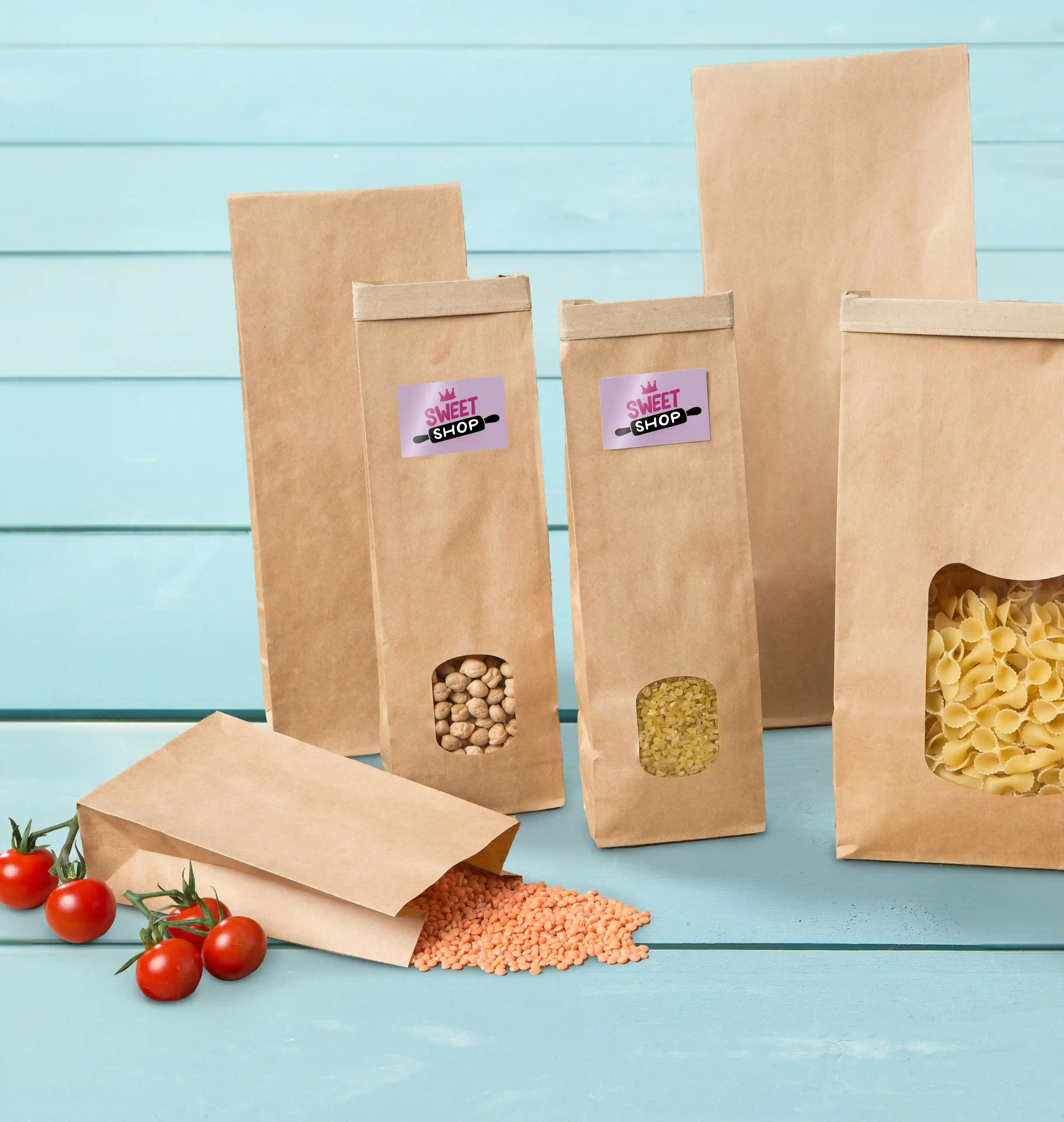 Sacs en papier brun avec divers contenus, y compris des lentilles et des pâtes, sur une surface en bois bleue.