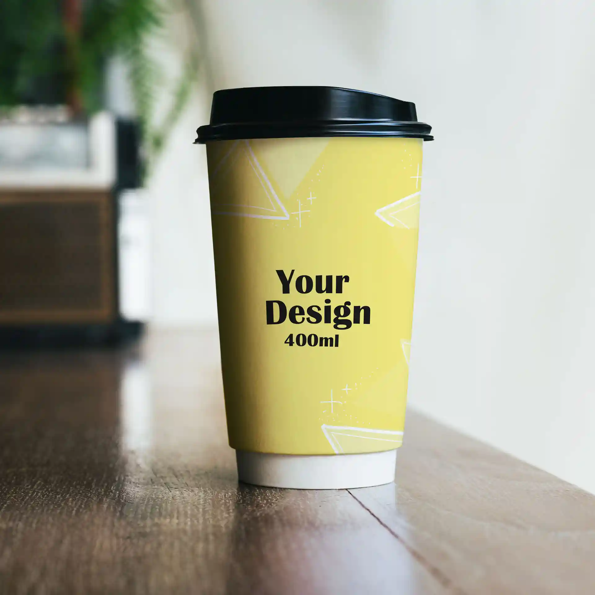 Bicchiere di carta a doppia parete con design giallo, coperchio nero e indicazioni di capacità di 400 ml su una superficie di legno.