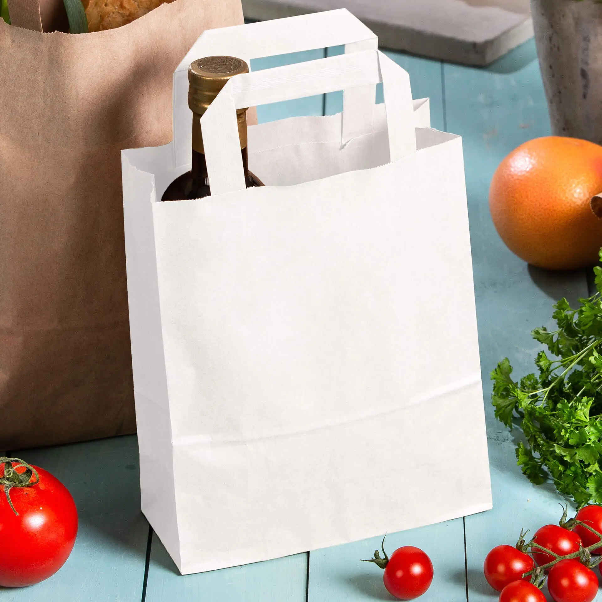 Weißer Tragetasche mit Henkel, die eine Flasche hält, neben Tomaten und anderen Lebensmitteln platziert.