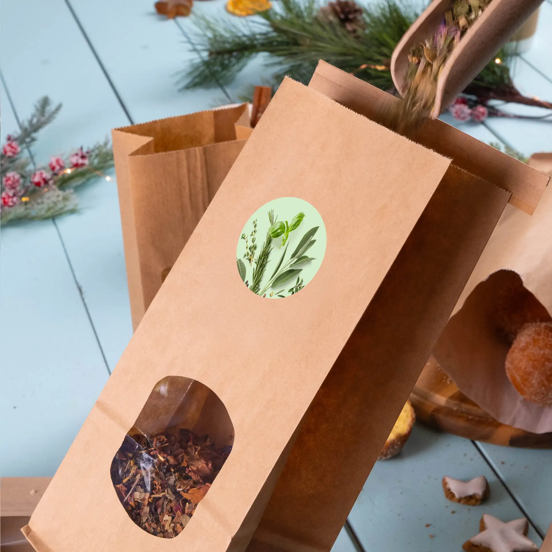 Borsa in carta kraft marrone con una finestra trasparente che mostra tè sfuso, un'etichetta personalizzata con immagini di erbe verdi e erbe versate.