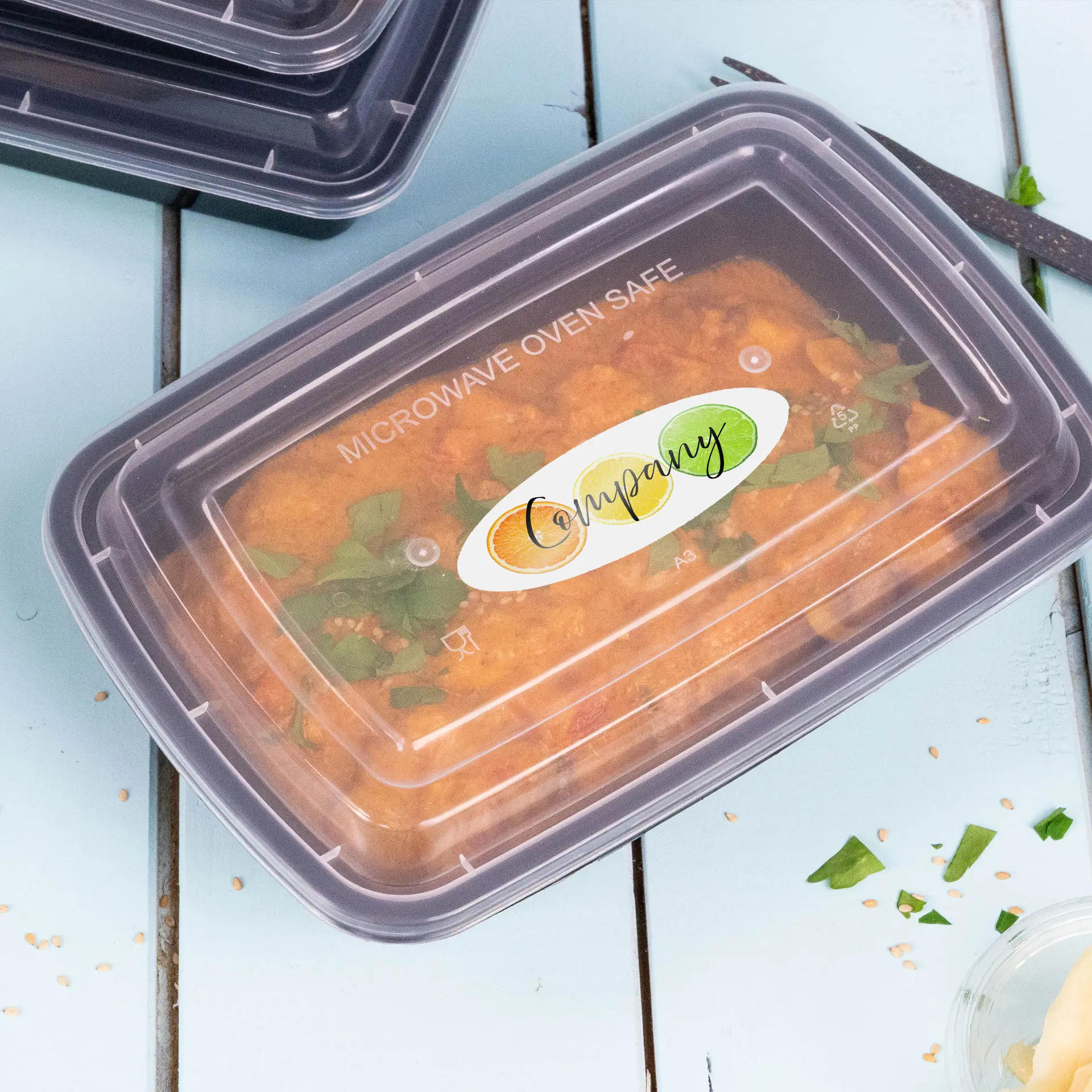 Conteneur alimentaire en plastique transparent avec un couvercle adapté aux micro-ondes, portant une étiquette affichant le nom et le logo de l'entreprise.