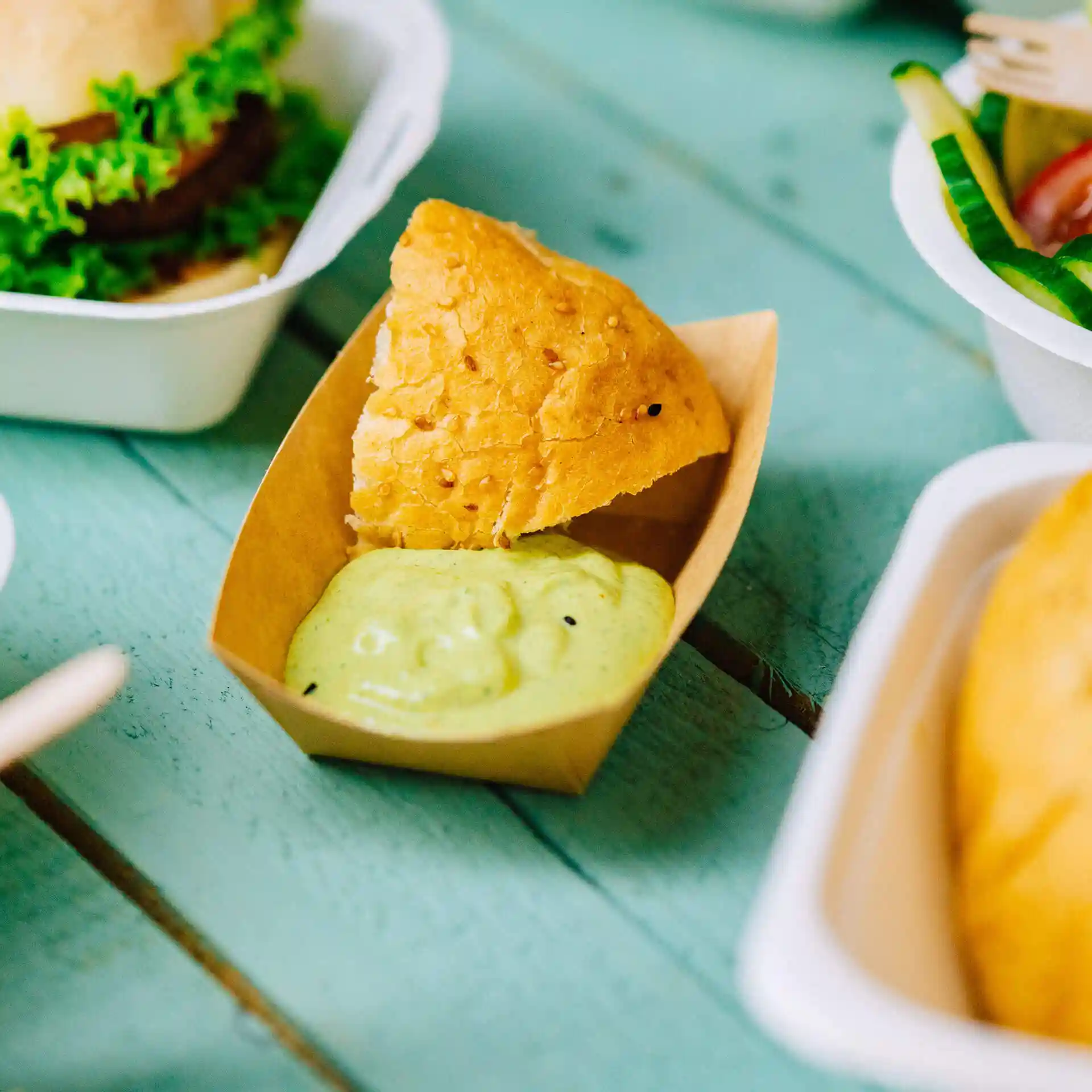 Vassoio per snack in cartone marrone con un pezzo di pane fritto e salsa verde all'interno.