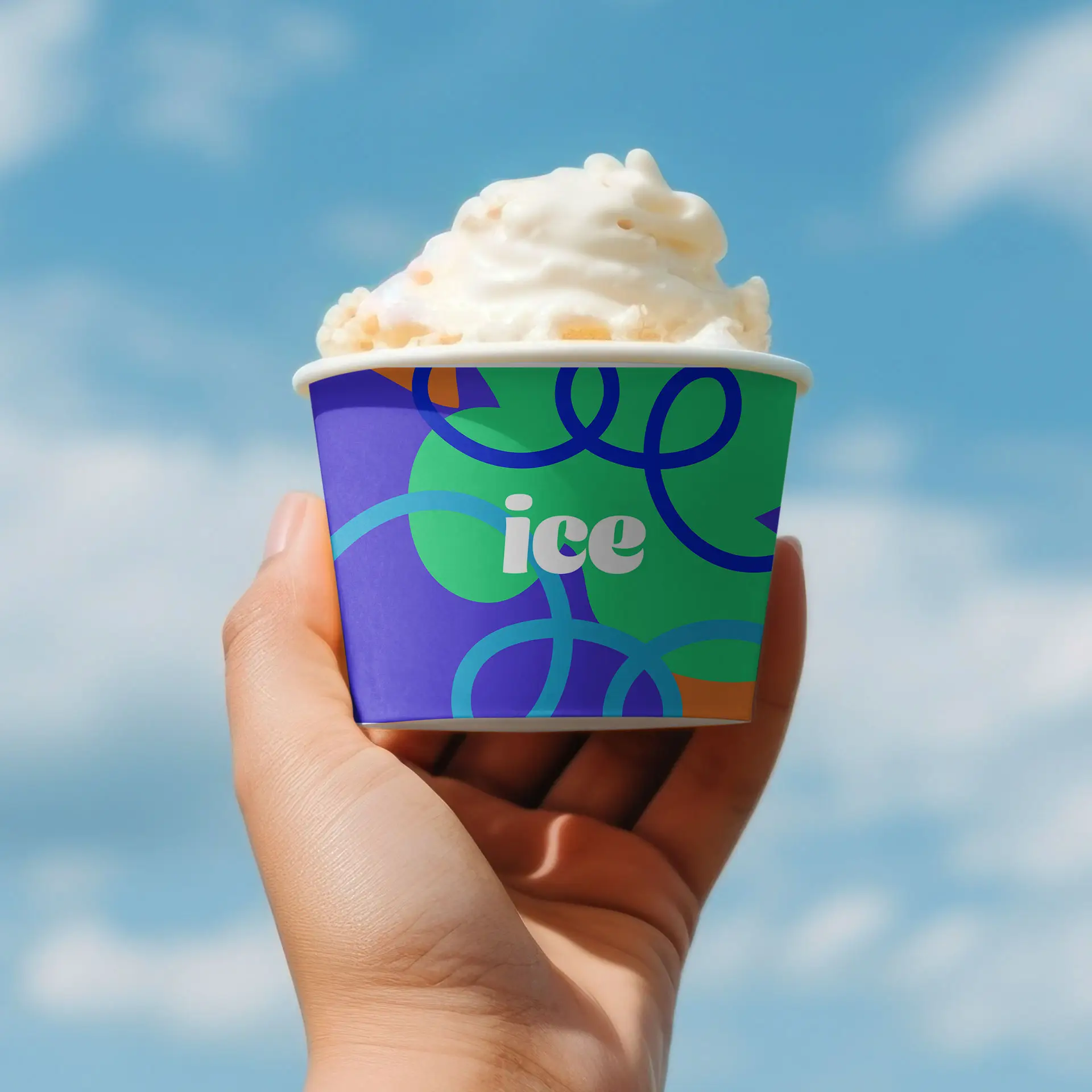 Gobelet à glace imprimé sur mesure tenu dans une main, avec un design coloré et le texte "ice", sur fond de ciel bleu.