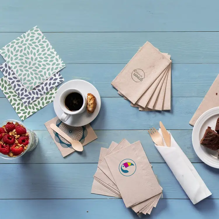 Disposition de table avec des serviettes à motifs, tasse de café avec biscuit, dessert et framboises fraîches dans un verre.