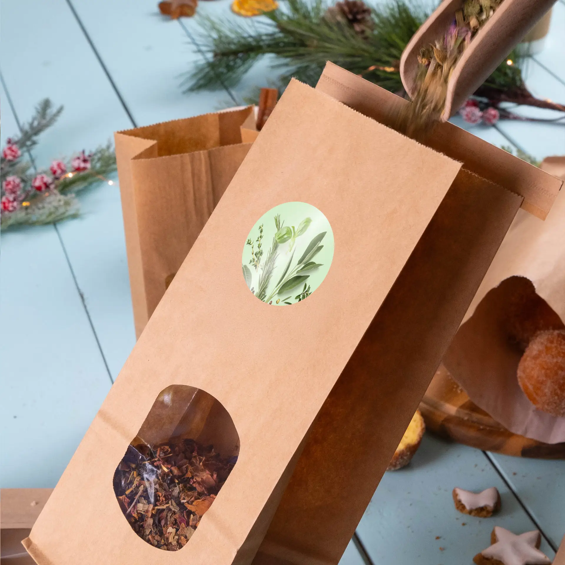 Una busta di carta kraft marrone con un'etichetta verde circolare e una finestra trasparente, piena di ingredienti per tè alle erbe sfusi.
