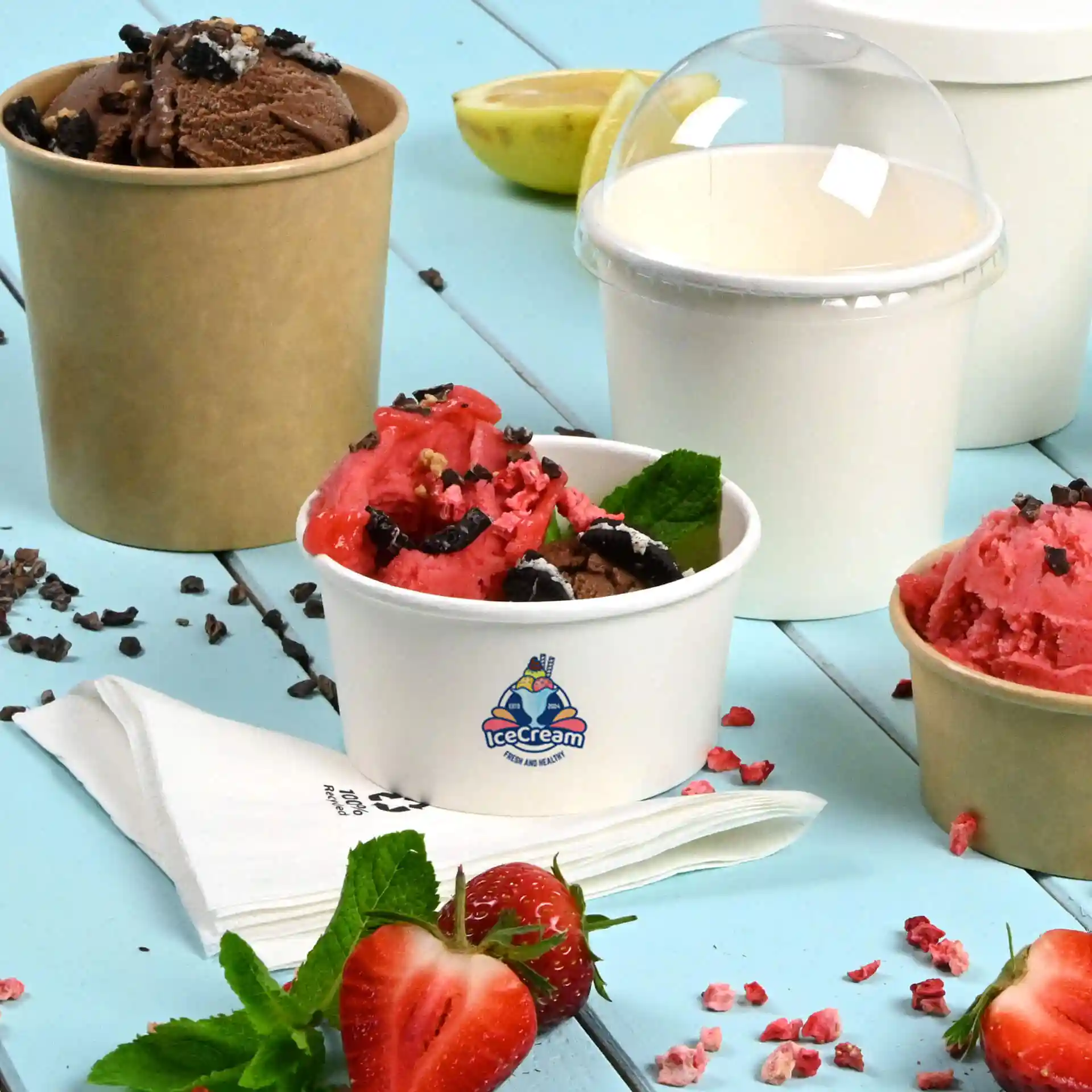 Image de plusieurs coupes de glace : une blanche avec un logo remplie de glace rose et brune, une brune avec de la glace au chocolat, et une coupe blanche simple.