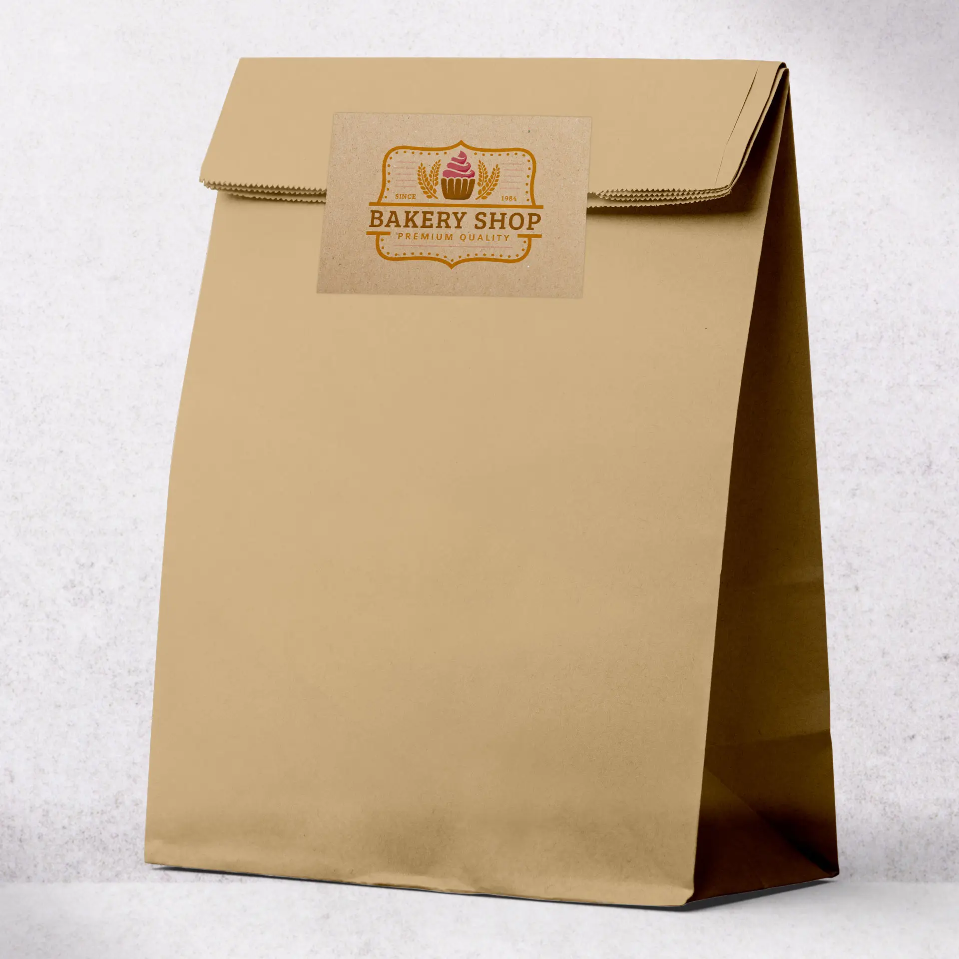 Sac en papier kraft marron avec une zone d'étiquette imprimée à l'avant affichant le logo d'une boulangerie.