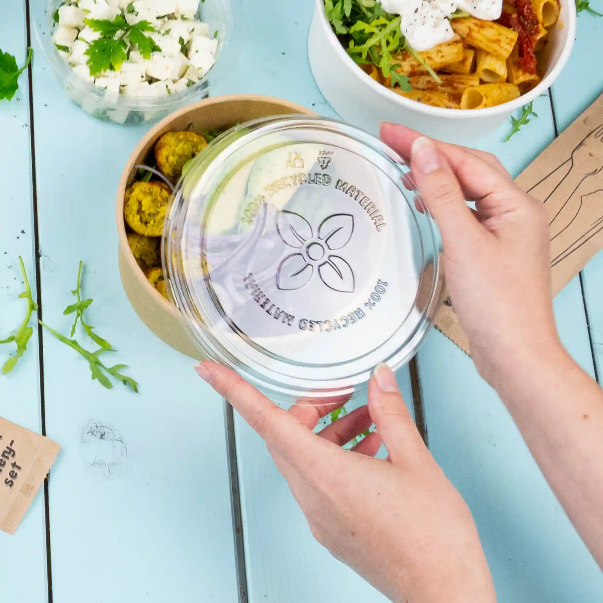 Couvercle rond transparent en rPET, tenu au-dessus d'un bol contenant des aliments.