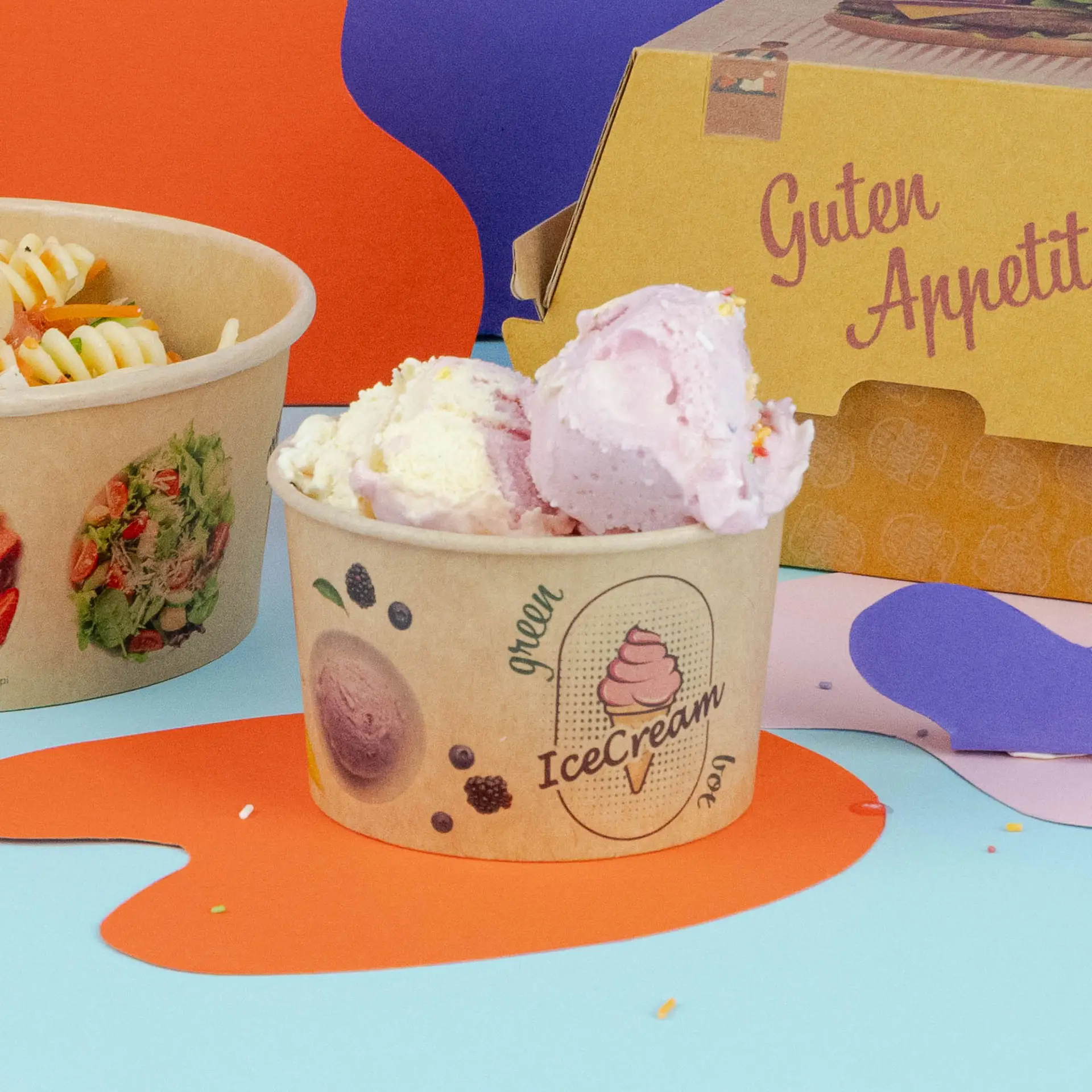 Coupe de glace brune avec des boules de glace rose et blanche, à côté d'un bol de pâtes et d'une boîte à emporter.