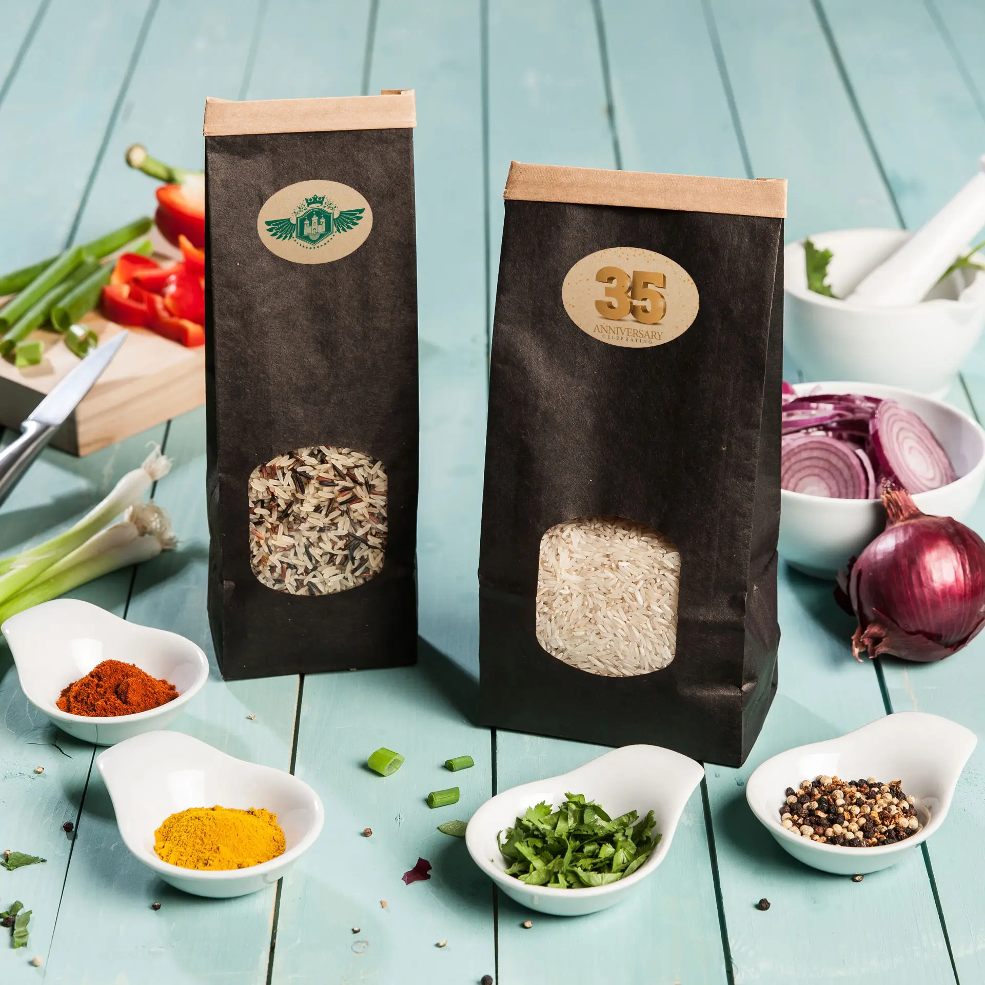 Zwei Papiertüten Reis, eine mit braunem Basmati-Reis und eine mit weißem Reis, auf einer blauen Holzoberfläche mit verstreuten Gewürzen.