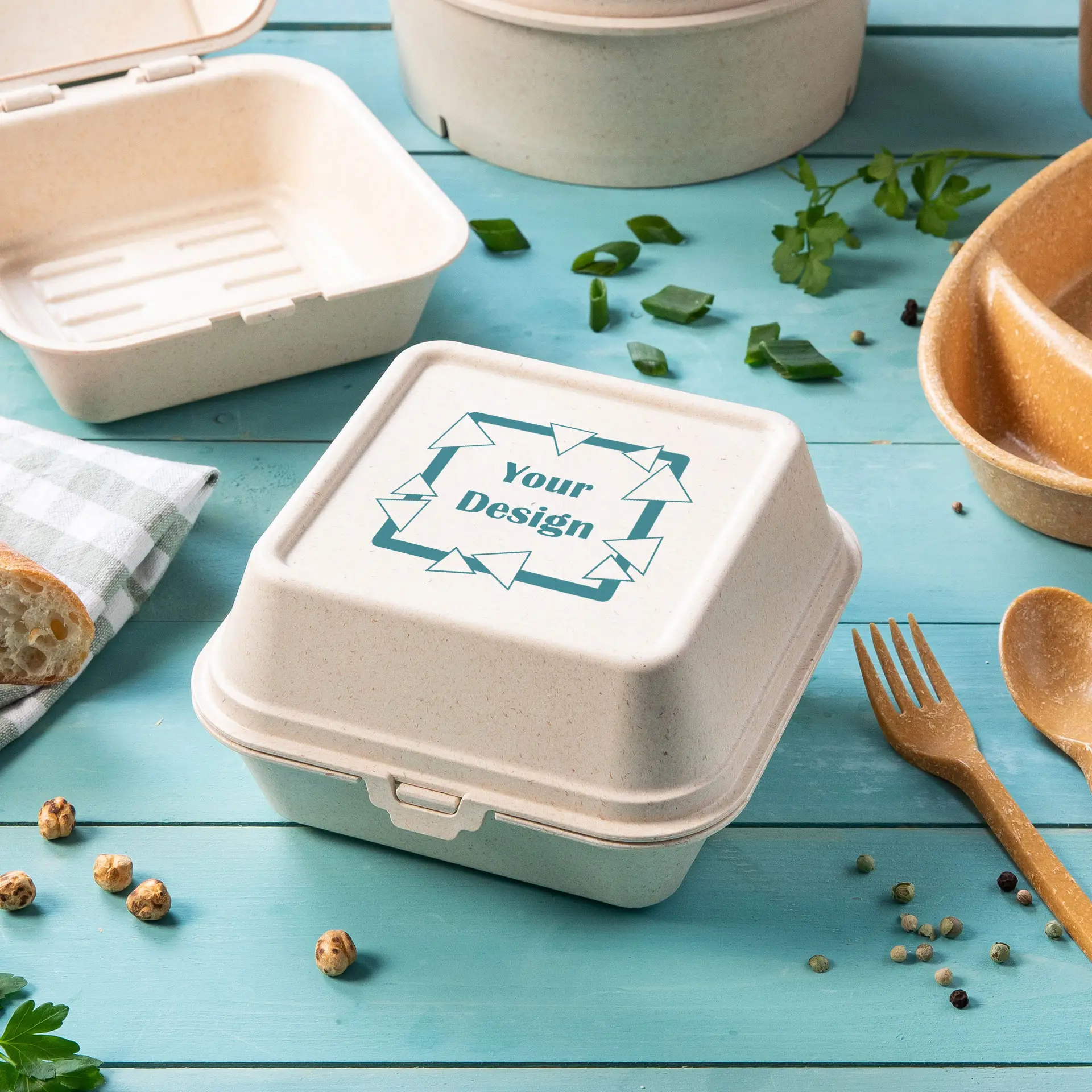 Scatola per hamburger riutilizzabile in bio-composito di legno, con coperchio personalizzabile, tra cibi e utensili.