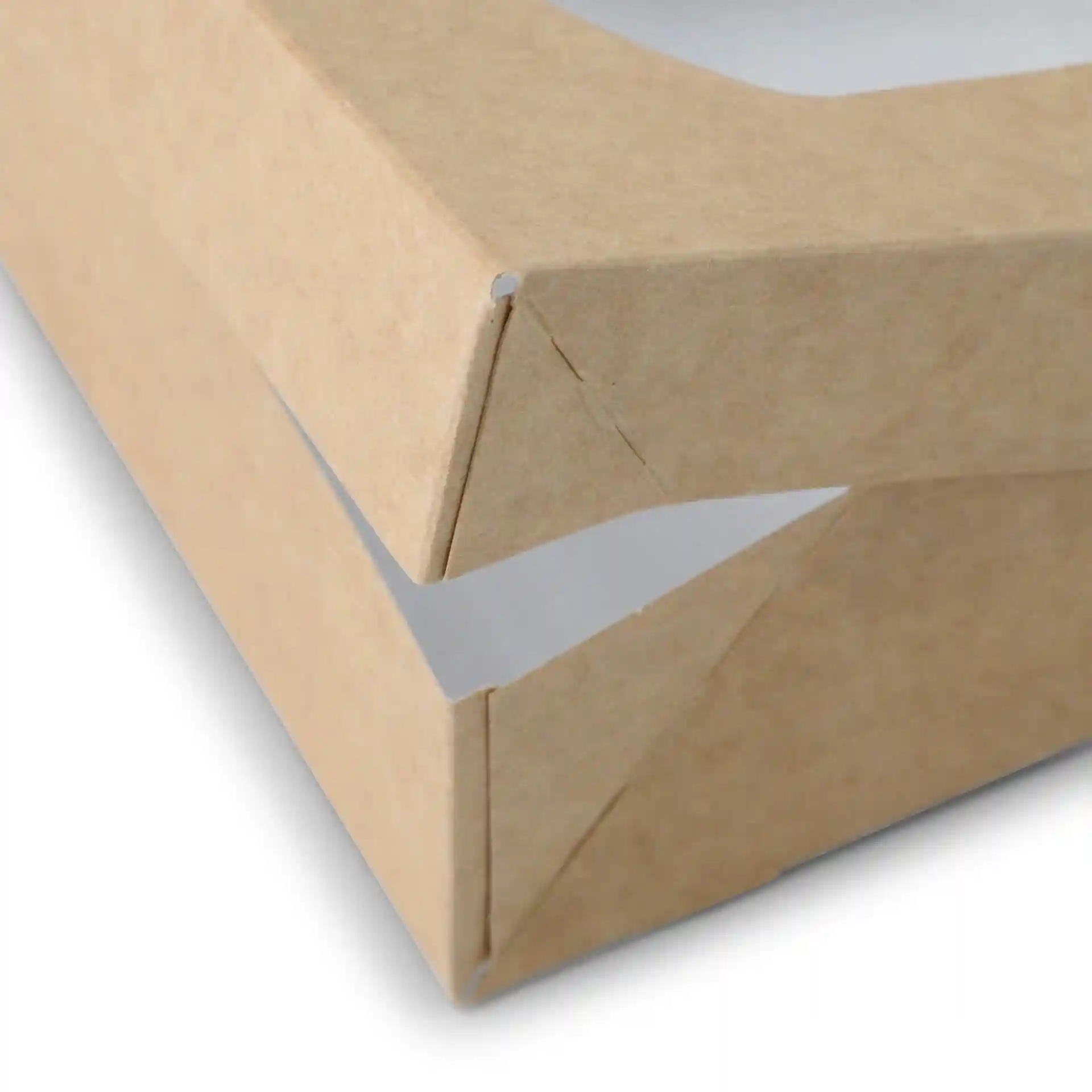 Gros plan d'une boîte en carton brun avec un intérieur blanc, montrant le coin et le détail de pliage.